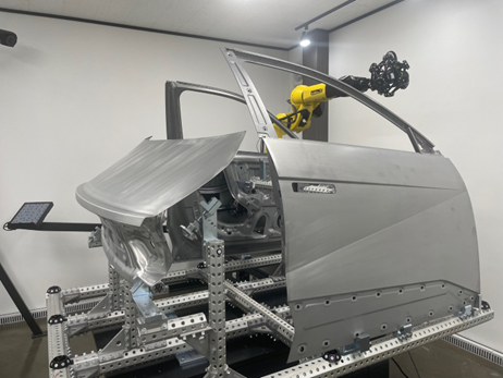 Un système CUBE-R qui inspecte une porte et des panneaux arrière montés sur un gabarit modulaire dans une salle de métrologie d’Ajin Industrial.